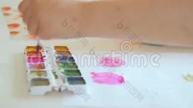 孩子们`艺术家的手拿起画笔上的颜料。